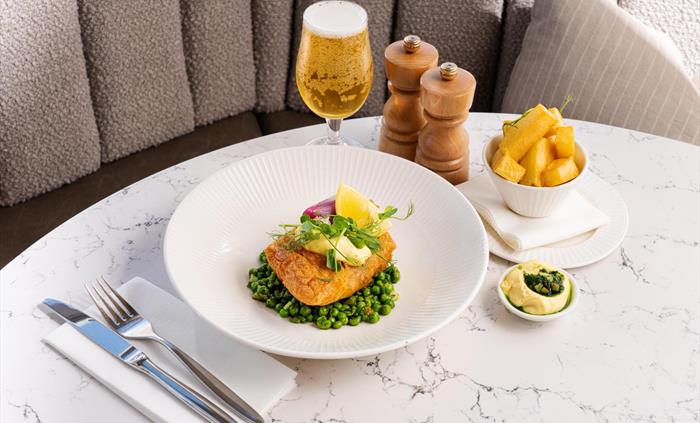 Image of fish and chips on a table, served with beer, at The Goat Restaurant